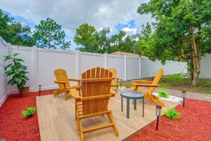 Eine Terrassenausstattung mit Adirondack-Stühlen, einem kleinen runden Tisch und einem Topfpflanzen.
