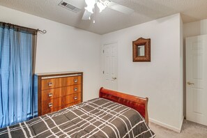 Un dormitorio con cama, cómoda y ventilador de techo.
