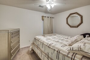 Un dormitorio con cama, cómoda, ventilador de techo y espejo en la pared.