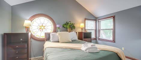 A bedroom with a bed, a dresser, a nightstand, a lamp, a window, and a ceiling fan.