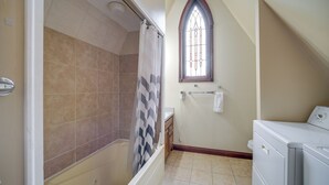 Ein Badezimmer mit Dusche, einem Fenster mit Buntglas und einer Waschmaschine.