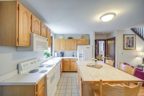 A kitchen with wooden cabinets, a stove, a refrigerator, and a dining table with chairs. - 6 Mi to Dtwn! Historic Haven in Cleveland (Cleveland)