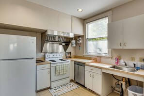 Eine Küche mit Kühlschrank, Herd, Backofen, Geschirrspüler und einem Fenster mit Jalousien.