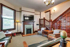 Una sala de estar con chimenea, televisor, una escalera y un espacio de descanso.