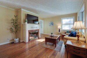 Una sala de estar con pisos de madera, chimenea, televisor, sofá y una lámpara.