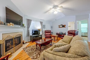 A living room with a fireplace, television, leather chairs, and a ceiling fan. - Ski & Hike! Cozy Sapphire Retreat (Sapphire)