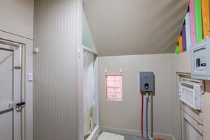 Une pièce avec une porte blanche, une fenêtre, un radiateur blanc et un panneau de commande.