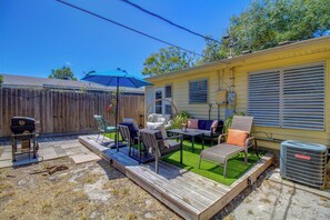 Ein Garten mit Terrasse, Gartenmöbeln, Grill und Rasen.