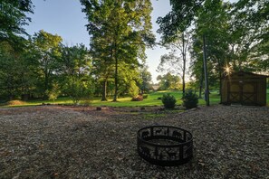 A gravel area with a metal fence and a wooden structure in the background.