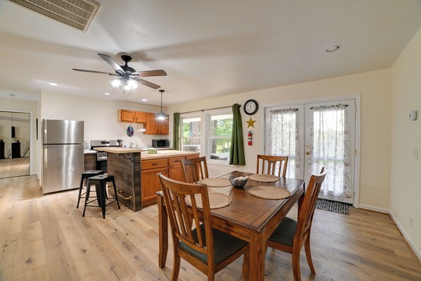 A modern kitchen with a central island, wooden chairs, and a dining table.