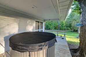 A covered outdoor area with a hot tub, wooden deck, and a view of a garden and trees. - Fall Foliage & Hot Tub Nights: Shawnee Cabin (Elizabethtown)