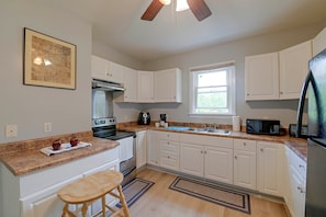A kitchen with white cabinets, a stove, a microwave, and a coffee maker. - Spacious Troy Unit Near Dtwn Shops & Dining (Troy)