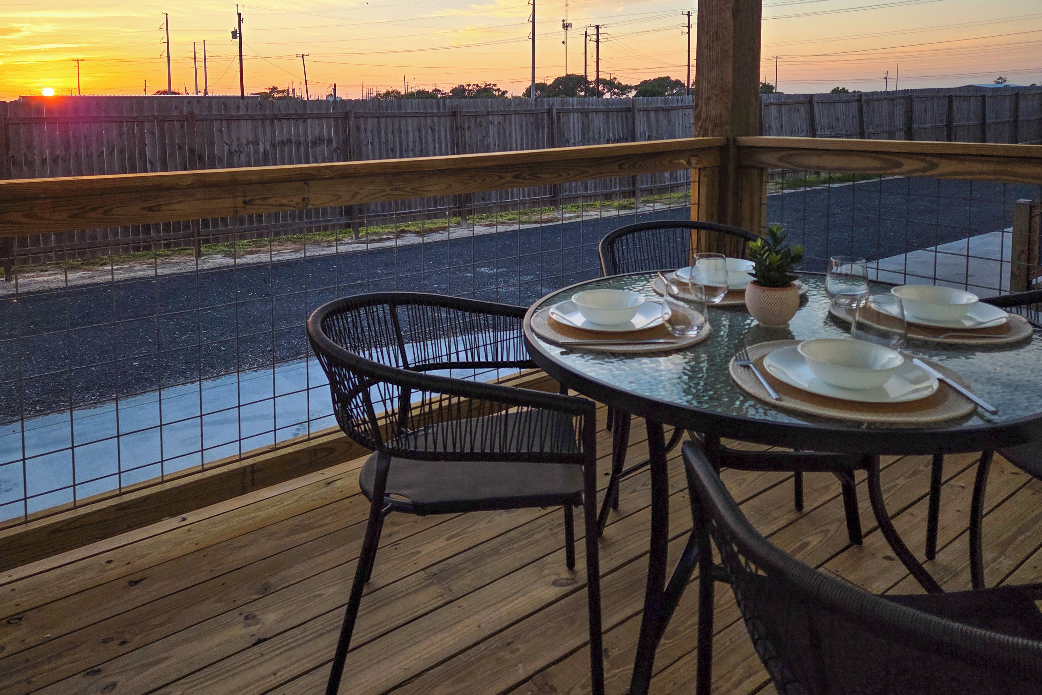 Zona de comedor al aire libre con vistas a un río y al atardecer.