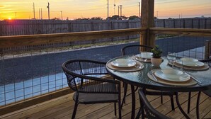 Un espace extérieur aménagé pour prendre les repas, avec vue sur une rivière et le coucher du soleil.