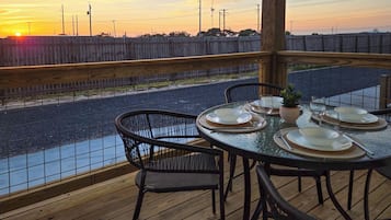 Zona de comedor al aire libre con vistas a un río y al atardecer.
