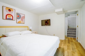 Una camera da letto con un letto, un comodino, una lampada, una TV e una scala.