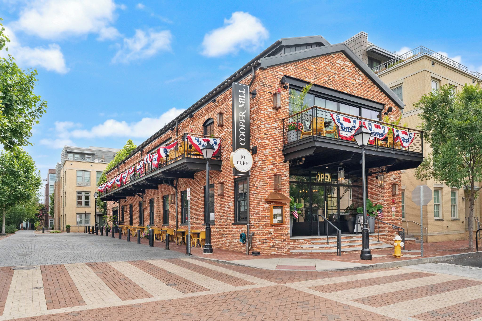 A brick building with a storefront, outdoor seating, and American flags.