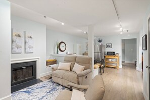 A modern living room with a sofa, fireplace, and a dining area with a microwave. - Walkable Old Town Retreat Near the Waterfront (Alexandria)
