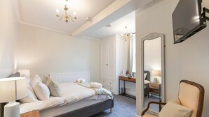 A bedroom with a bed, bedside table, chair, and a large mirror. - Standard Double Room (Derby)