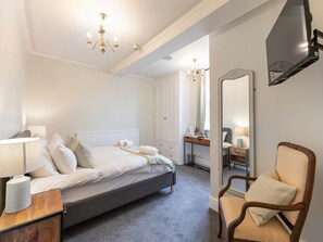 A bedroom with a bed, bedside table, chair, and a large mirror. - Standard Double Room (Derby)