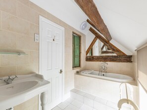 A bathroom with a white door, a bathtub, a sink, and a mirror. - Standard Double Room (Derby)