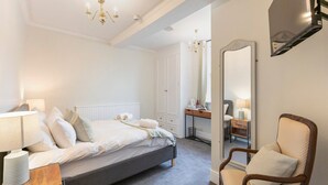 A bedroom with a bed, bedside table, chair, and a large mirror. - Standard Double Room (Derby)
