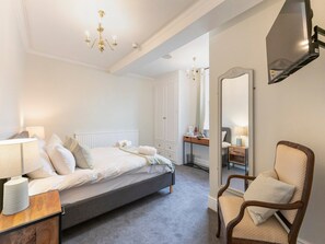 A bedroom with a bed, bedside table, chair, and a large mirror. - Standard Double Room (Derby)
