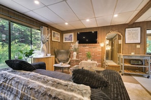 Ein gemütliches Zimmer mit großem Fenster, Flachbildfernseher, Kamin und Spiegel.