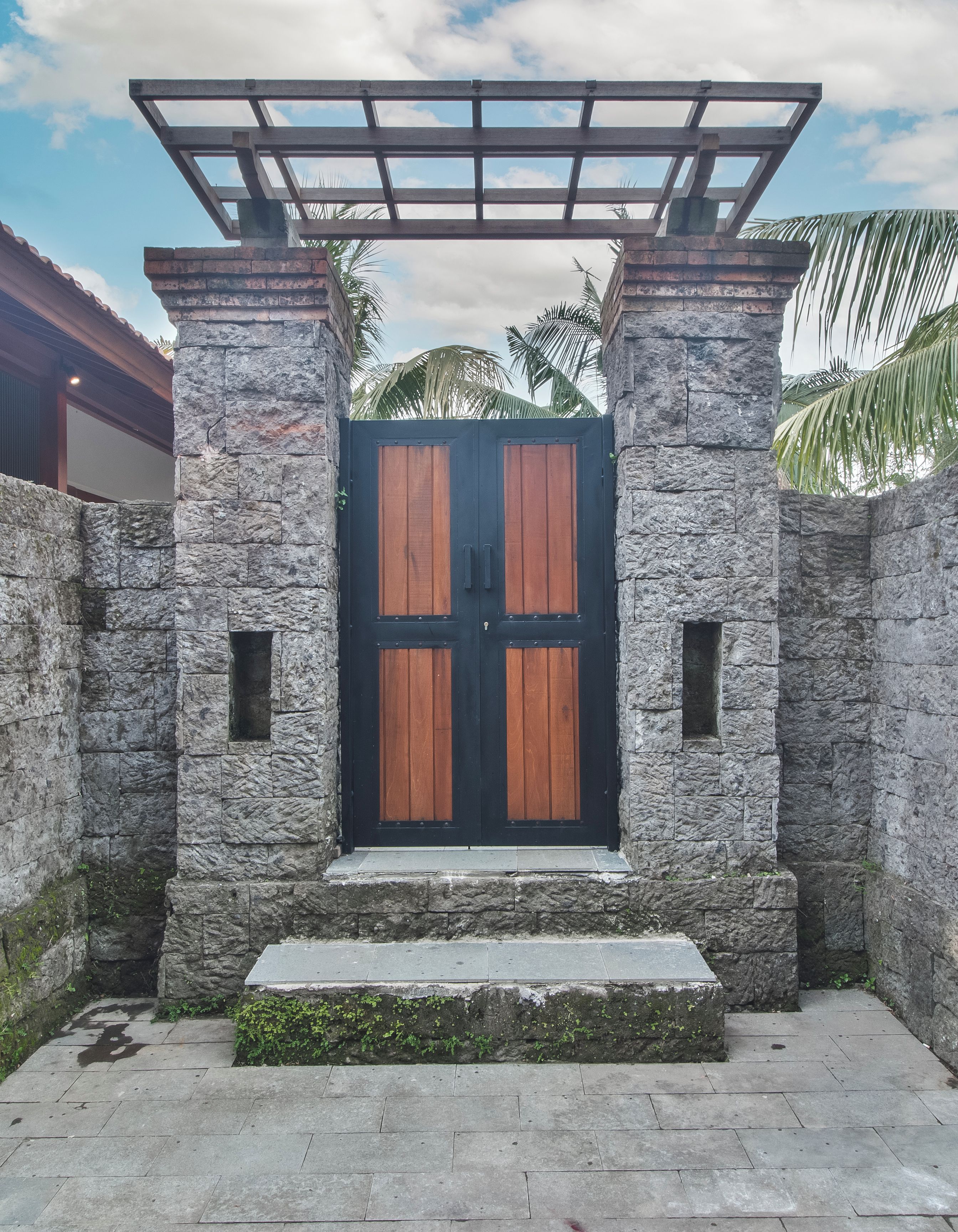 Un muro de piedra con una puerta de madera y un portón de metal.