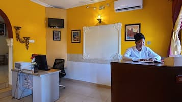 Un espace d’accueil d’hôtel comprenant un comptoir de réception, un téléviseur et un mur décoratif.