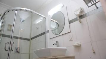Een badkamer met een douchecabine van glas, een wastafel, een spiegel en een handdoekhouder.