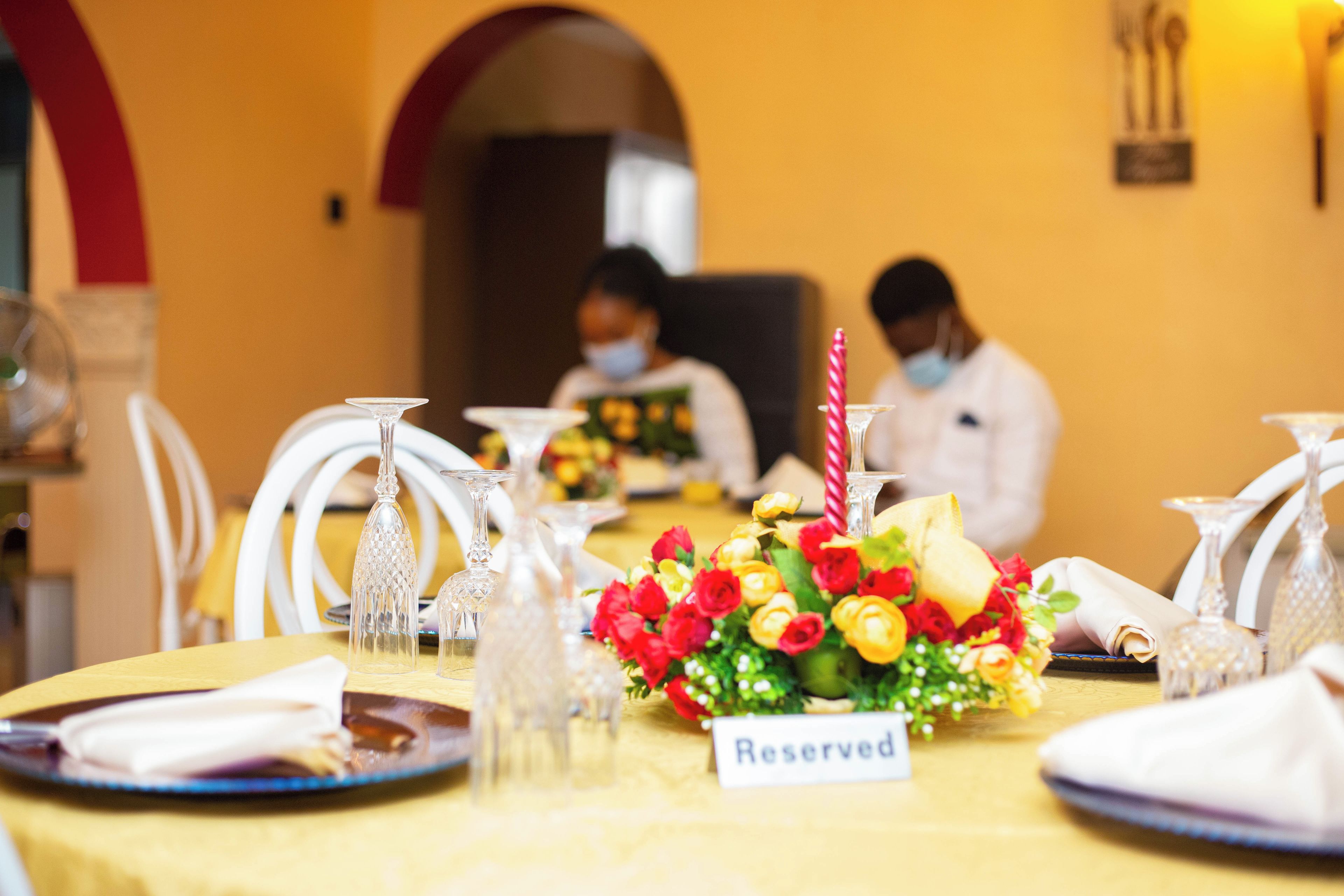 A dining table with a 'Reserved' sign, crystal glassware, and a floral centerpiece.