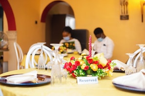 Una mesa de comedor con un cartel de 'Reserved', copas de cristal y un centro de mesa floral.