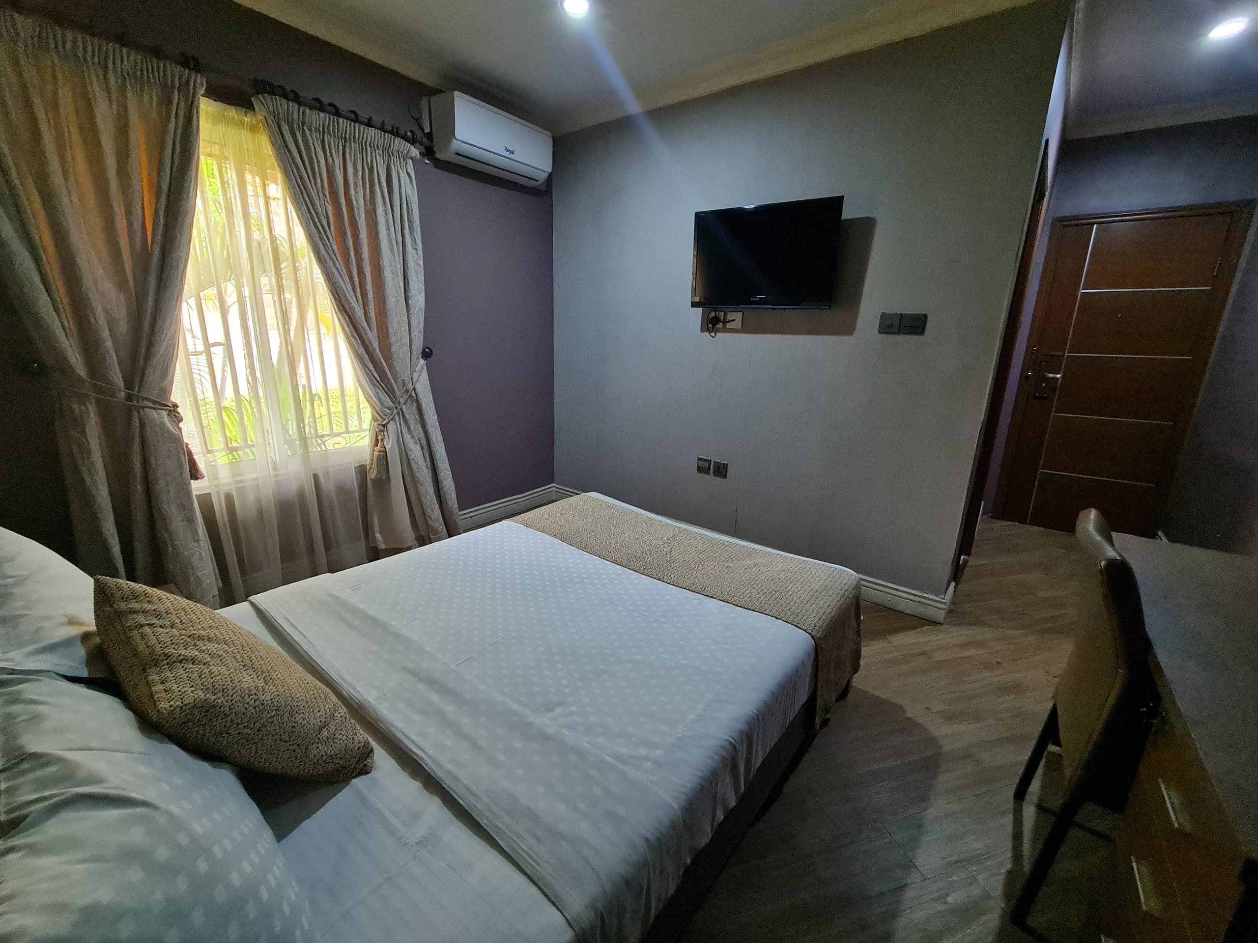 Une chambre d’hôtel équipée d’un lit, d’un bureau, d’un climatiseur, d’une télévision et d’une porte.