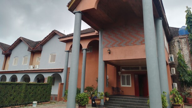 A building with a covered entrance, multiple columns, and a staircase leading to the entrance. - Quiet Pols Residence  (Lagos)