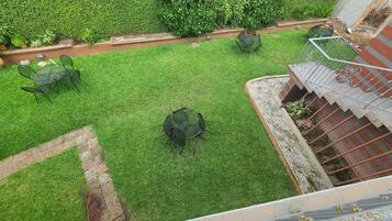 Un jardín en la azotea con una zona de estar pequeña y una escalera.