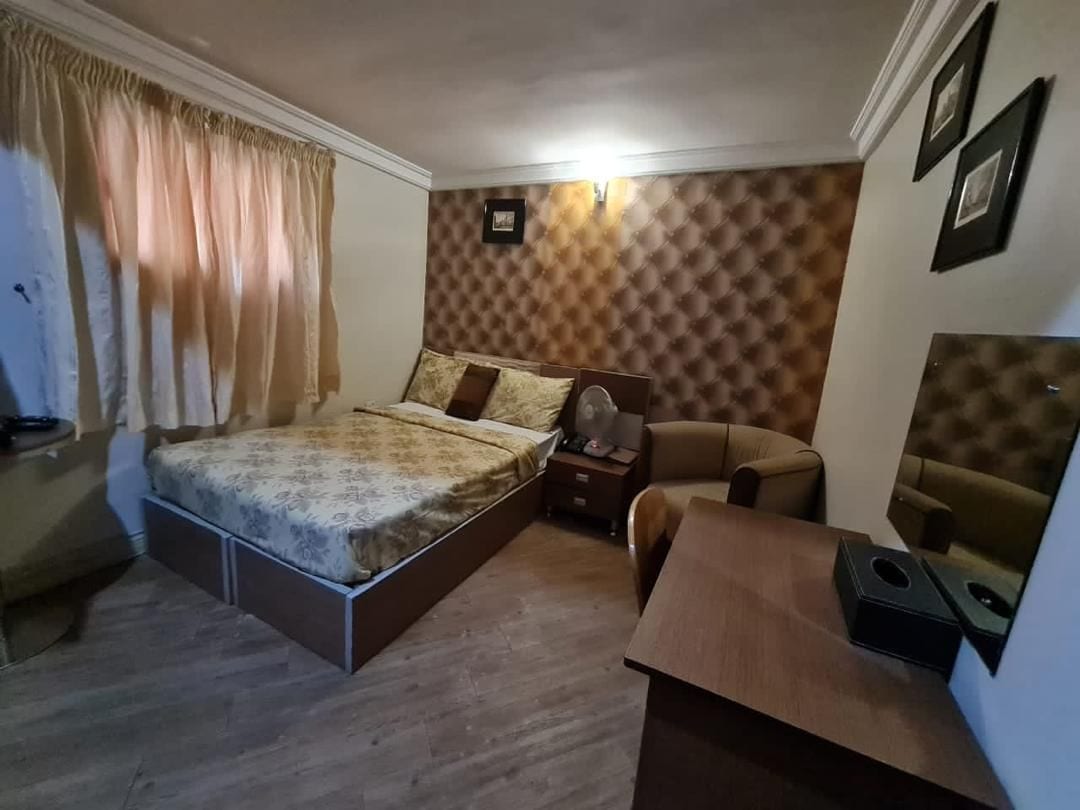 A bedroom with a bed, a nightstand, a chair, and a desk.