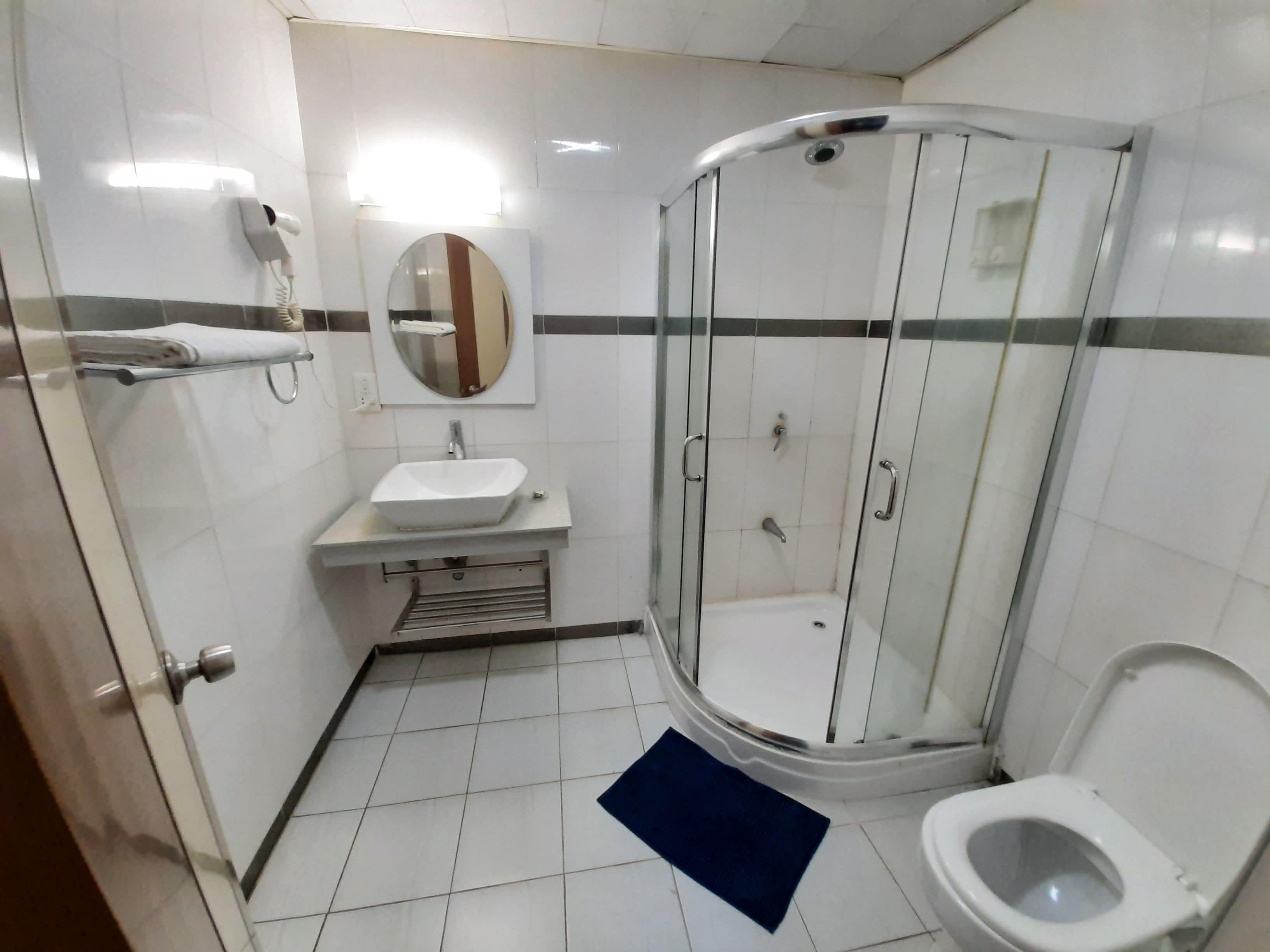 A bathroom with a glass-enclosed shower, a sink, and a toilet.