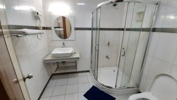 A bathroom with a glass-enclosed shower, a sink, and a toilet.