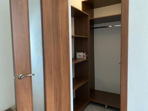Un placard en bois avec plusieurs étagères et une tringle pour suspendre les vêtements.