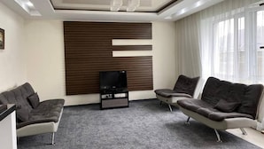 A modern living room with a flat-screen TV, two sofas, and a large window. - Mirano Guest House Hostel  (Karakol town)