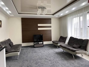 Ein modernes Wohnzimmer mit einem Flachbildfernseher, zwei Sofas und einem großen Fenster.
