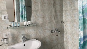 A bathroom with a sink, mirror, shower, and tiled walls. - Mirano Guest House Hostel  (Karakol town)