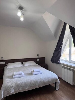 Un dormitorio con cama, una ventana con cortinas, un radiador y una lámpara en el techo.