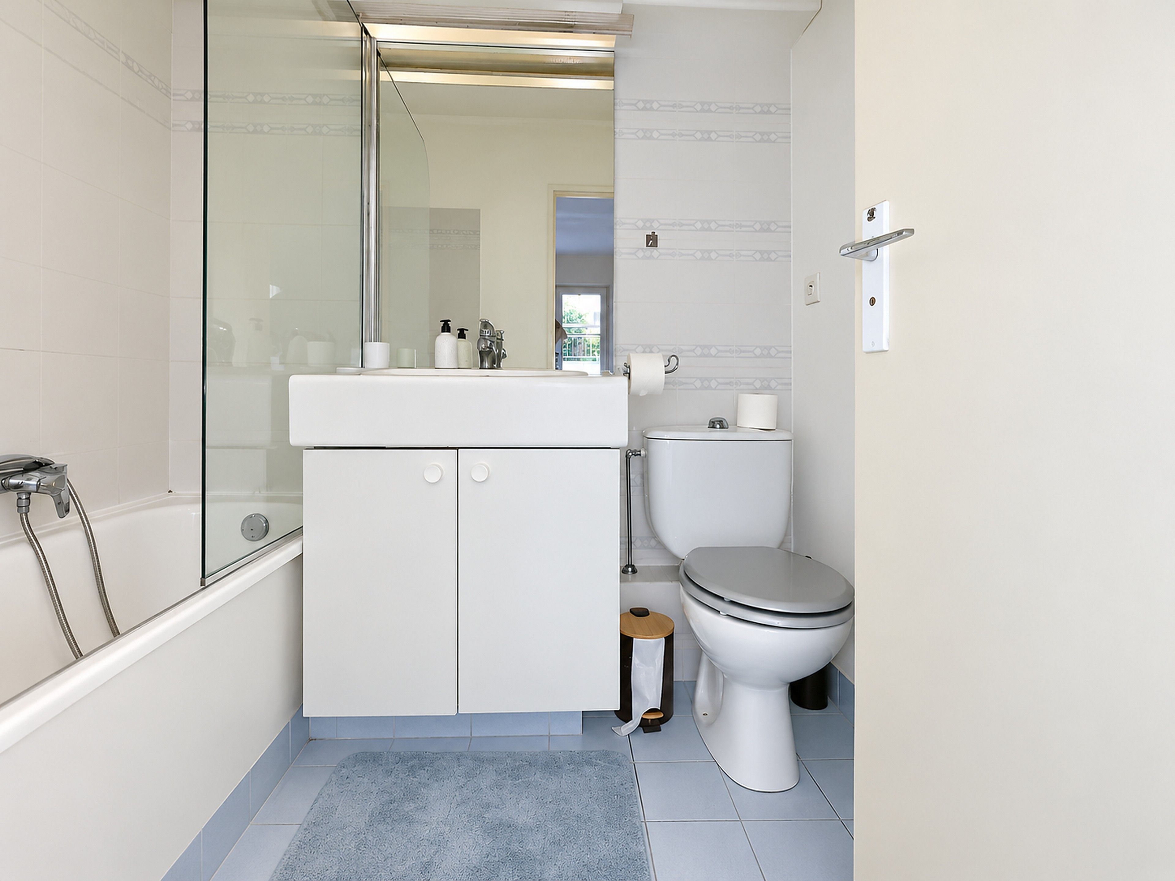 Un bagno moderno con doccia vetrata, lavandino bianco con articoli da toilette, water e pavimento in moquette blu.