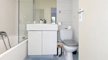 Un bagno moderno con doccia vetrata, lavandino bianco con articoli da toilette, water e pavimento in moquette blu.