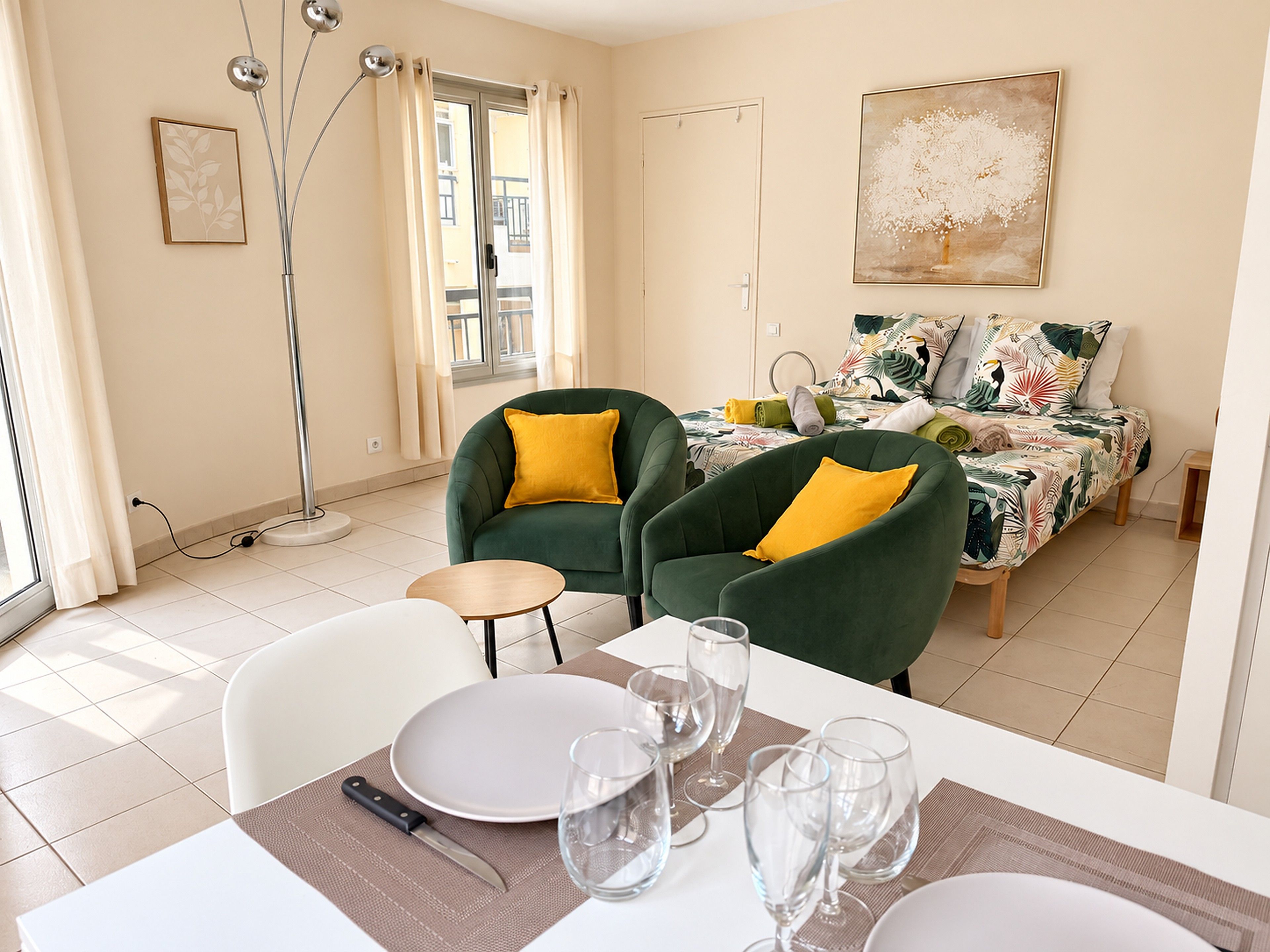 A dining area with a table set for four, chairs, and a floor lamp.