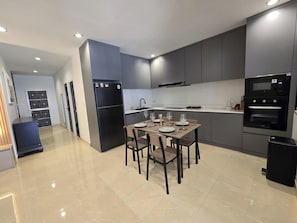 A modern kitchen with a dining area, equipped with a refrigerator, oven, and microwave. - 2BR Condo Near City Center (NG430) (Hua Hin)