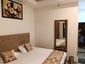 A bedroom with a large bed, a mirror, and a painting on the wall. - RS Resort (Chirgaon)