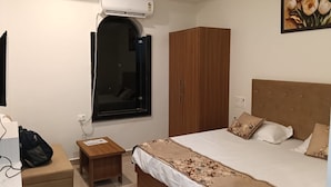 Ein Schlafzimmer mit Bett, Kleiderschrank, einem kleinen Tisch, einer Klimaanlage und einem Fenster.